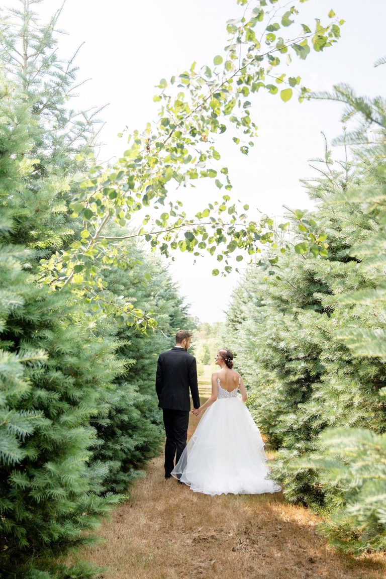 Carly Caleb Arrowwood Farms Wedding Walking between pines 768x1152